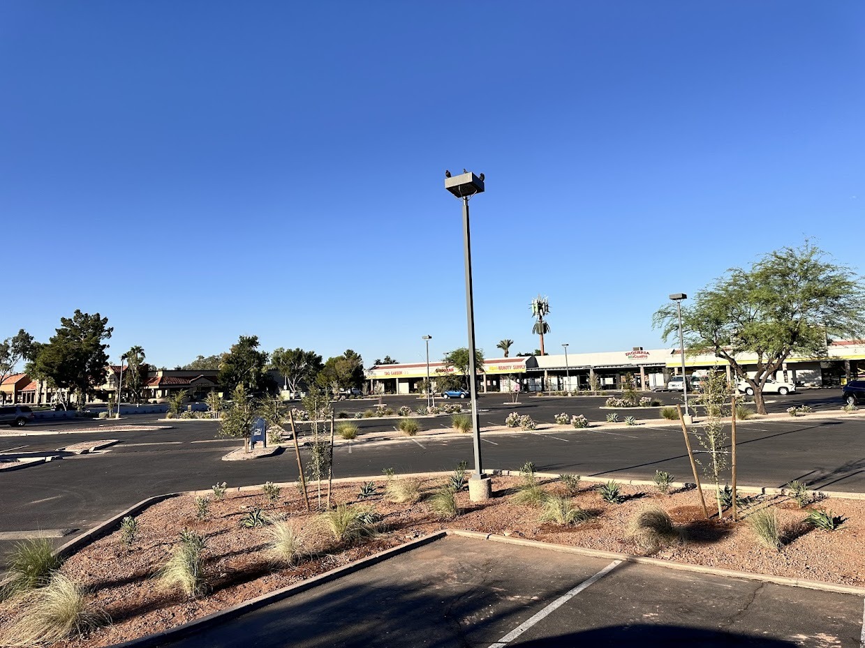 Empty parking lot with shops and clear sky.