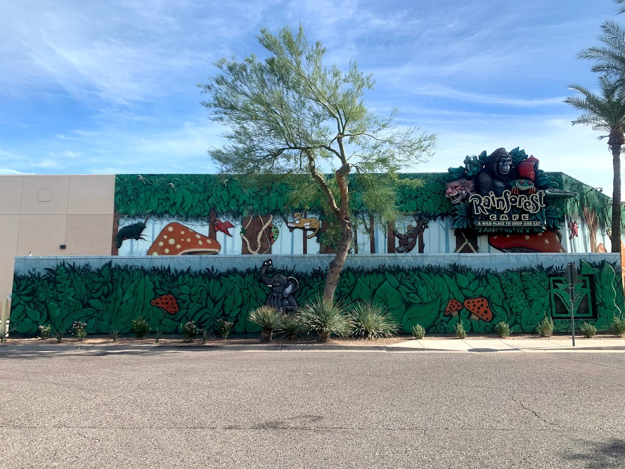 Rainforest-themed building with mural and sign.
