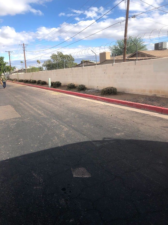 Quiet street with utility poles and barbed wire fence.