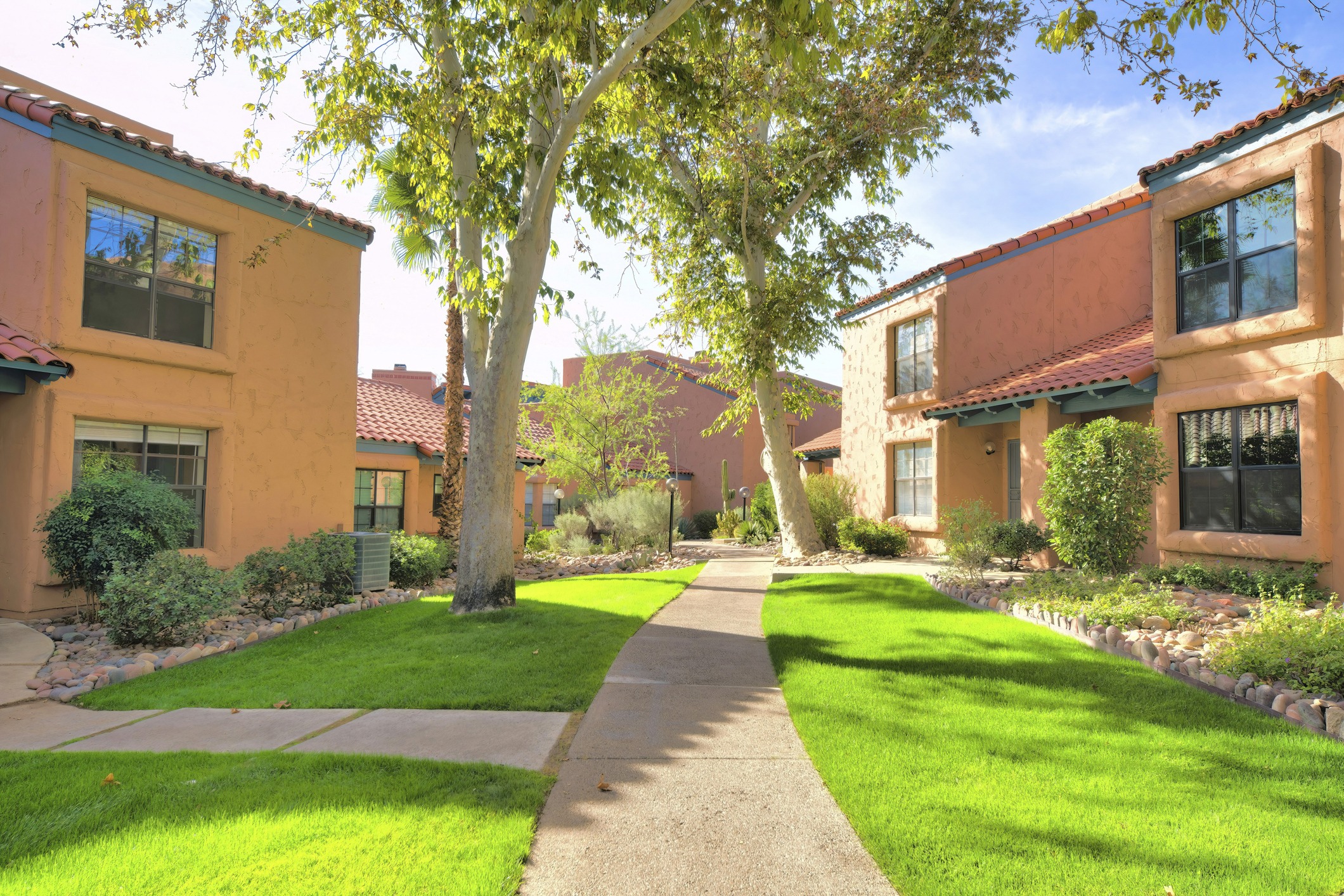 Sunny courtyard with orange buildings and green grass.