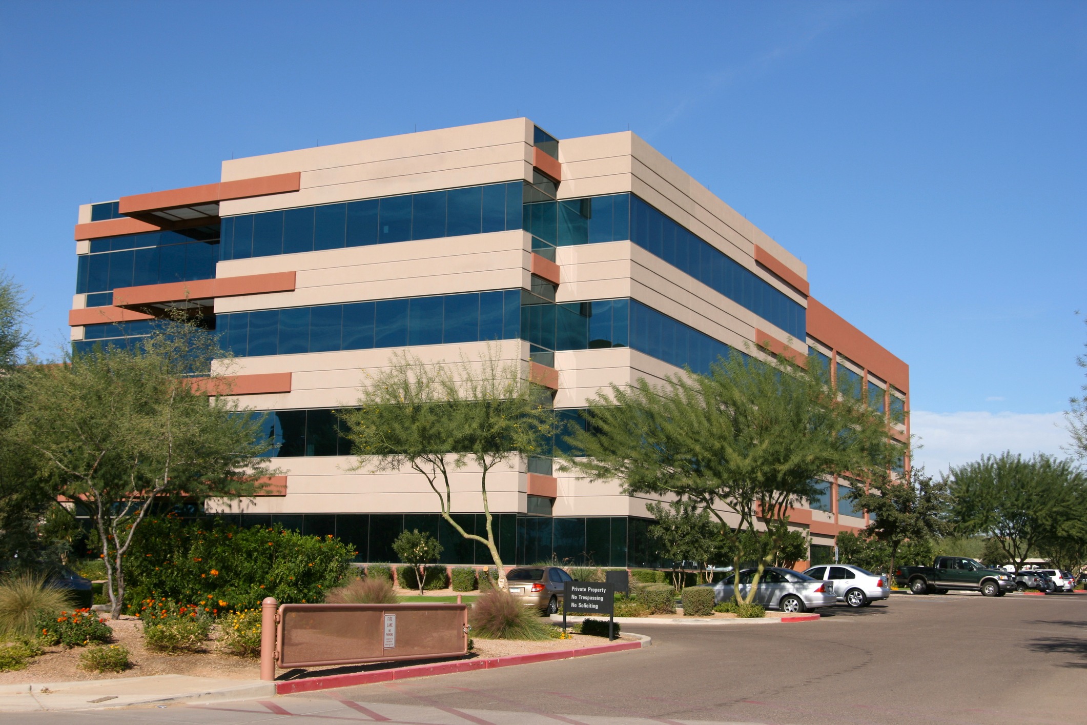 Modern office building with parking lot and trees.