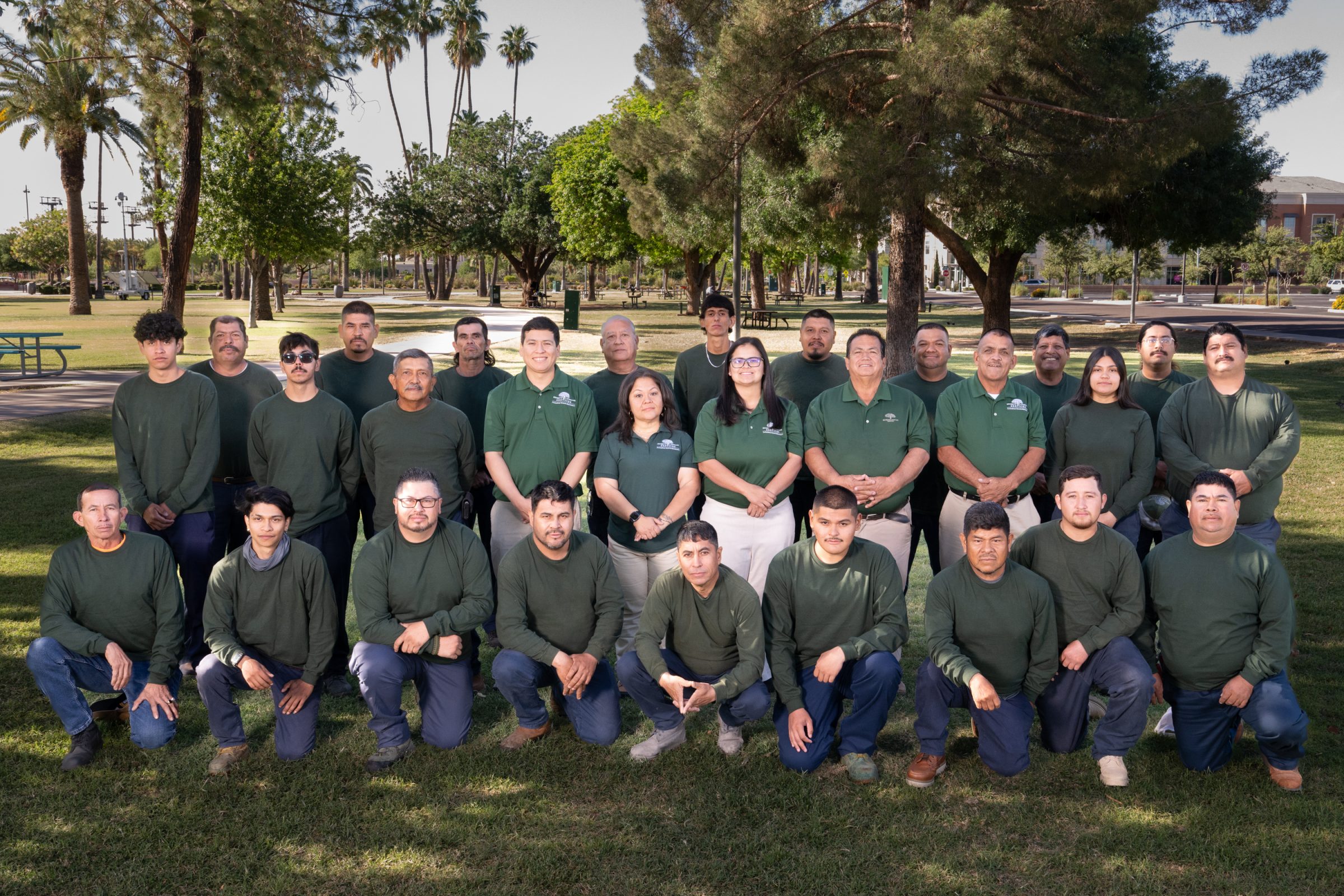 Group of employees wearing green shirts in a park.